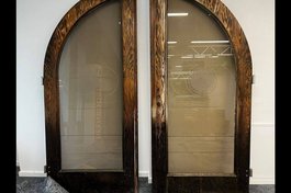 Doppeltür aus hölzernem Rahmen mit Innenflächen aus Glas mit einer Gravur 