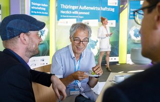 Drei männliche Personen unterhalten sich an einem Tisch.