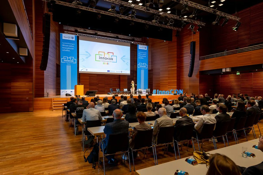 InnoCON Bildergalerie Menschen sitzen an Tischen in einem großen Auditorium