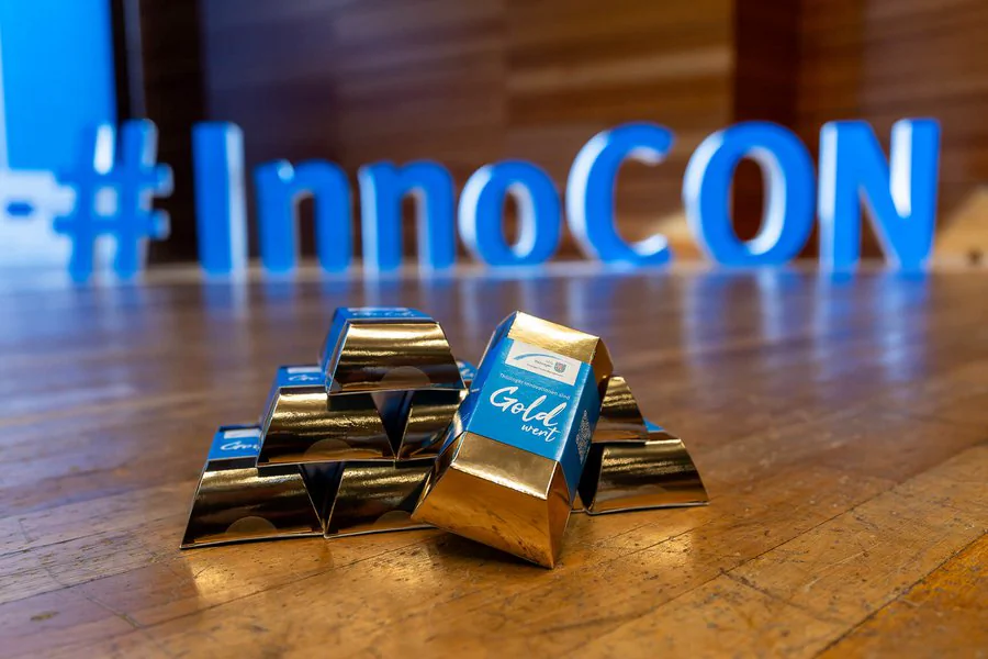 InnoCON Bildergalerie Foto, Goldbarren mit LEG Branding im Vordergrund, #InnoCON Schriftzug im Hintergrund