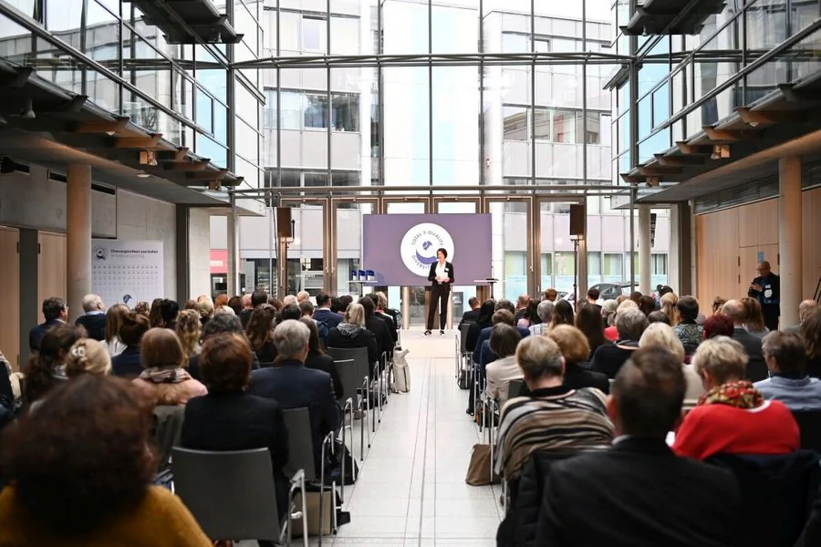 Eine große Menschenmenge ist im Atrium des COMCENTERs versammelt, während ein Redner auf der Bühne spricht.