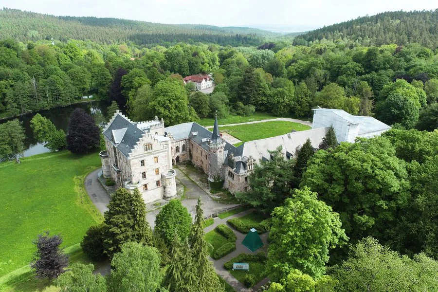 Luftaufnahme Schloss Reinhardsbrunn Luftaufnahme eines Schlosses, umgeben von üppigen Bäumen, die eine malerische Landschaft bilden.