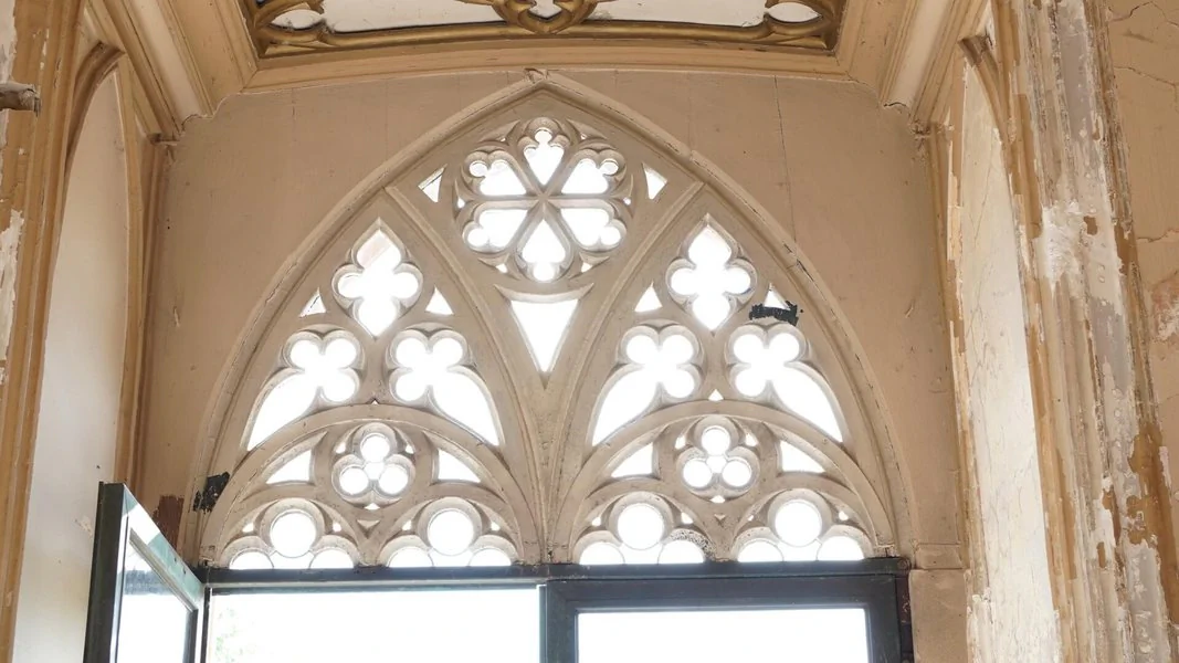 Verzierungen vom Schloss Reinhardsbrunn Ein Fenster mit gotischem Design, das kunstvolle Verzierungen und spitz zulaufende Bögen zeigt.
