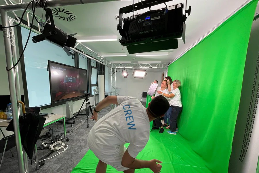 Ein Mann gibt Schauspielern vor einem grünen Hintergrund Tipps