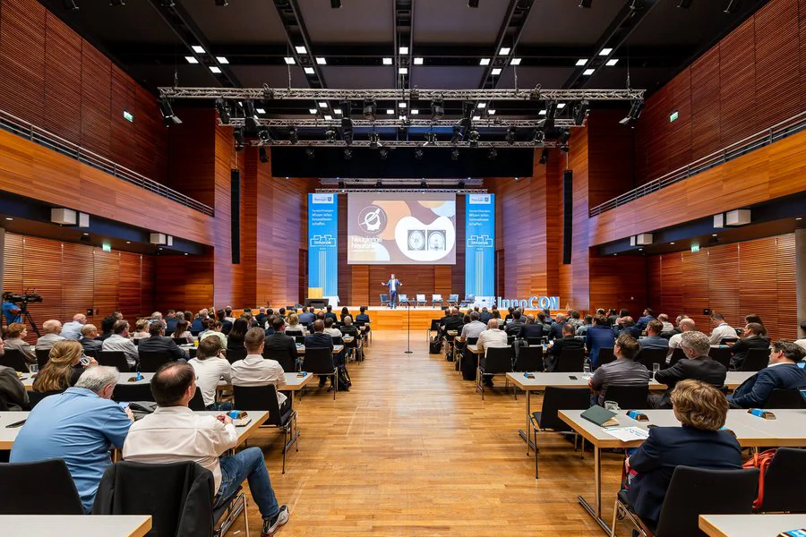 InnoCON Bildergalerie Menschen sitzen an Tischen in einem großen Auditorium