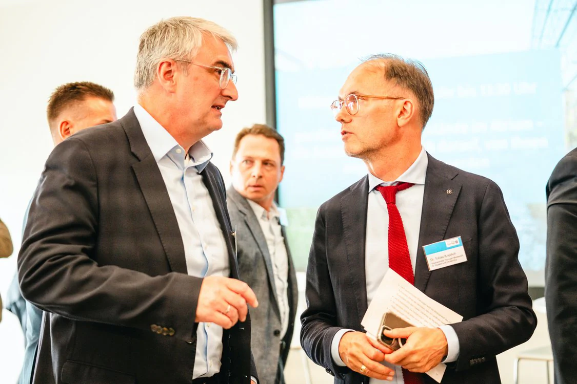 Copyright: TMDI / B. Schmidt Conversation at an event of the Thuringian Mobility Network: State Secretary Dr. Tobias Knoblich (right) in discussion with another participant. The image was taken in the context of the Thuringian Mobility Conference 2026 and shows the professional dialogue on mobility and regional development in Thuringia.