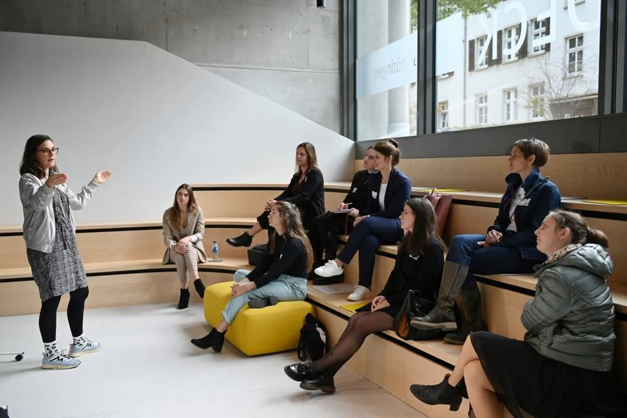 Eine Gruppe von Personen sitzt in einer Art Amphitheater und folgt einem Vortrag