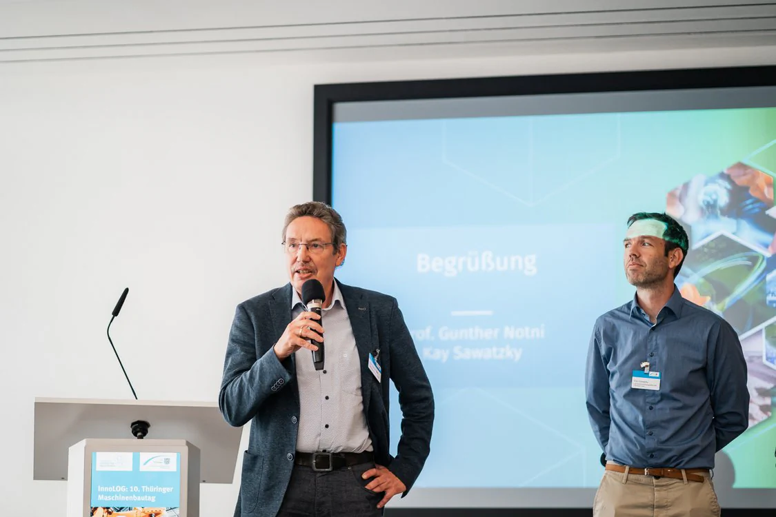 Zwei Referierende stehen vor einer Präsentationsleinwand und eröffnen den Maschinenbautag 2026.