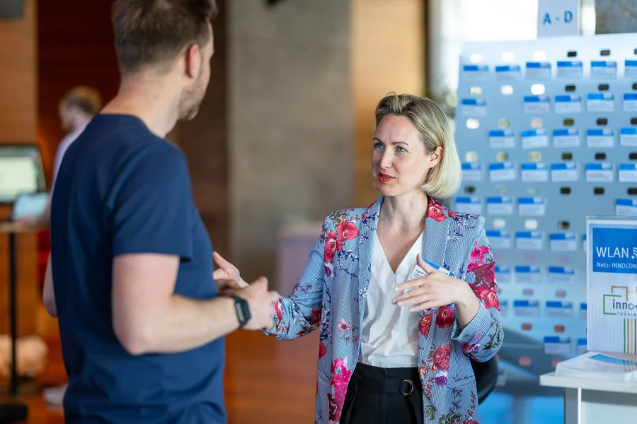 InnoCON Bildergalerie Eine Frau (Mitarbeiterin der LEG) und ein Mann unterhalten sich bei einer Veranstaltung.