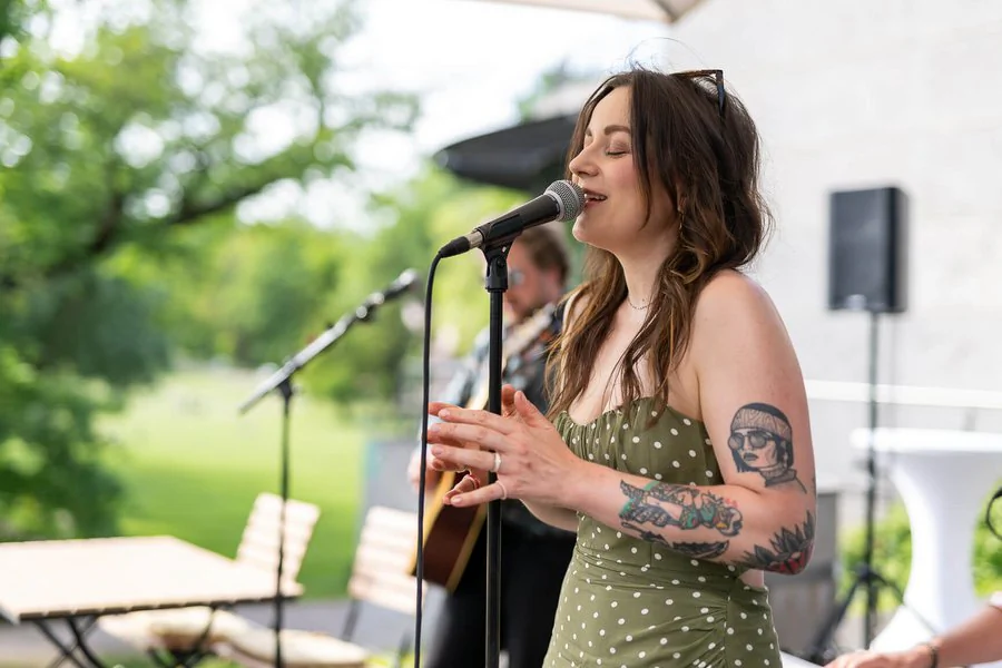 InnoCON Bildergalerie Eine tätowierte Frau singt bei einer Outdoor-Veranstaltung.