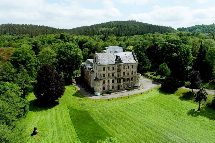 Luftaufnahme Schloss Reinhardsbrunn Luftaufnahme eines Schlosses, umgeben von üppigen Bäumen und einer großen Wiese.